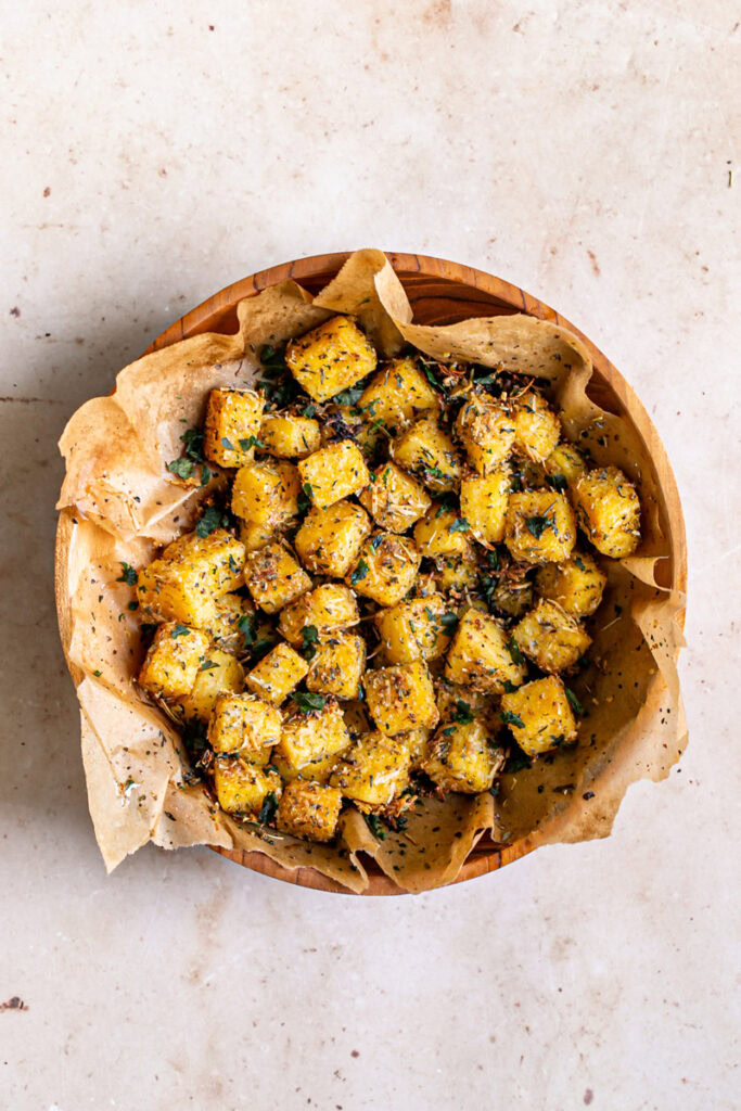 polenta croutons in a wooden bowl lined with parchment paper