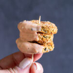 three air fried pickles on a toothpick with boom boom sauce dripping down the side