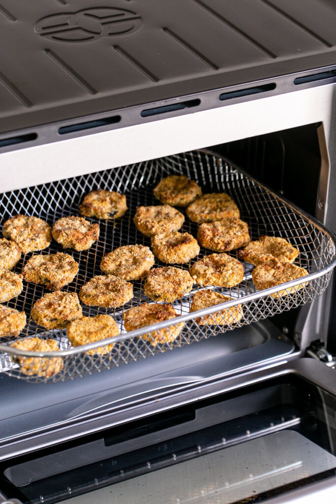 fried pickles in the air fryer basket sticking out of the air fry oven
