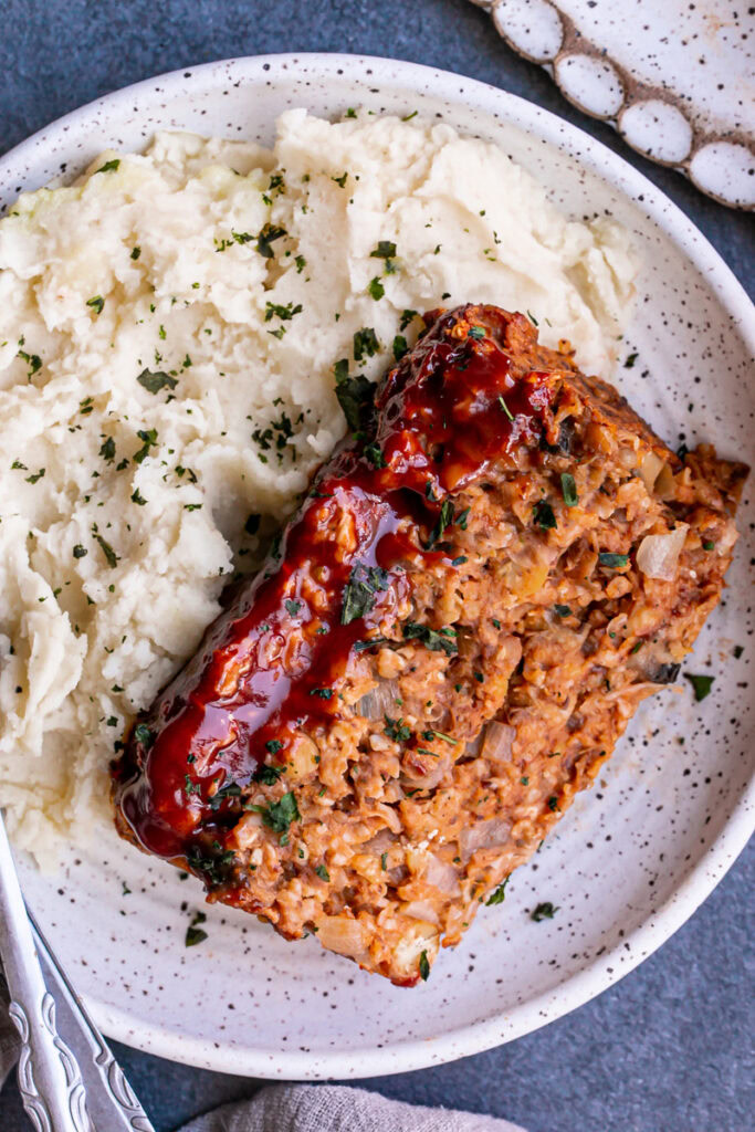a close up of Vegan Gluten-Free Meatloaf on a plate with mashed potatoes