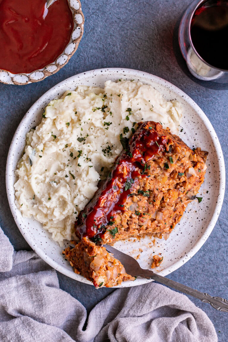 Vegan Gluten-Free Meatloaf on a plate with mashed potatoes and a piece of meatloaf cut off with a fork