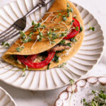 Vegan Gluten-Free Savory Pancake filled with vegan cheese, mushroom, kale and onion, and tomato on a plate garnished with fresh microgreens
