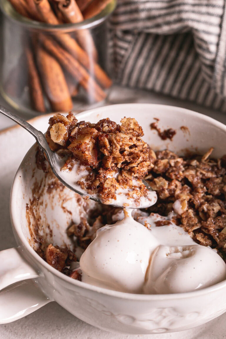 a close up action shot of scooping some cinnamon apple crisp out of the mug