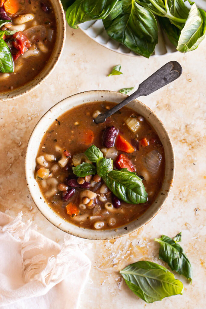 a bowl of easy plant based minestrone soup with a spoon in it