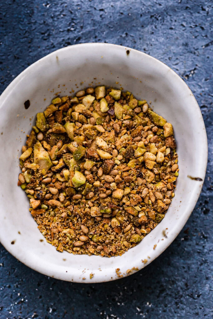 a small bowl of pistachio dukkah, roasted pistachios and sesame seeds combined with coriander, cumin, allspice, salt and pepper and pulsed in a food processor until coarse crumbs remain