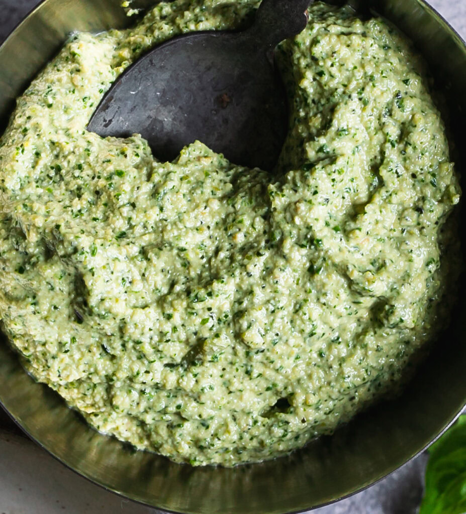 a bowl of blended pesto with a spoon in it