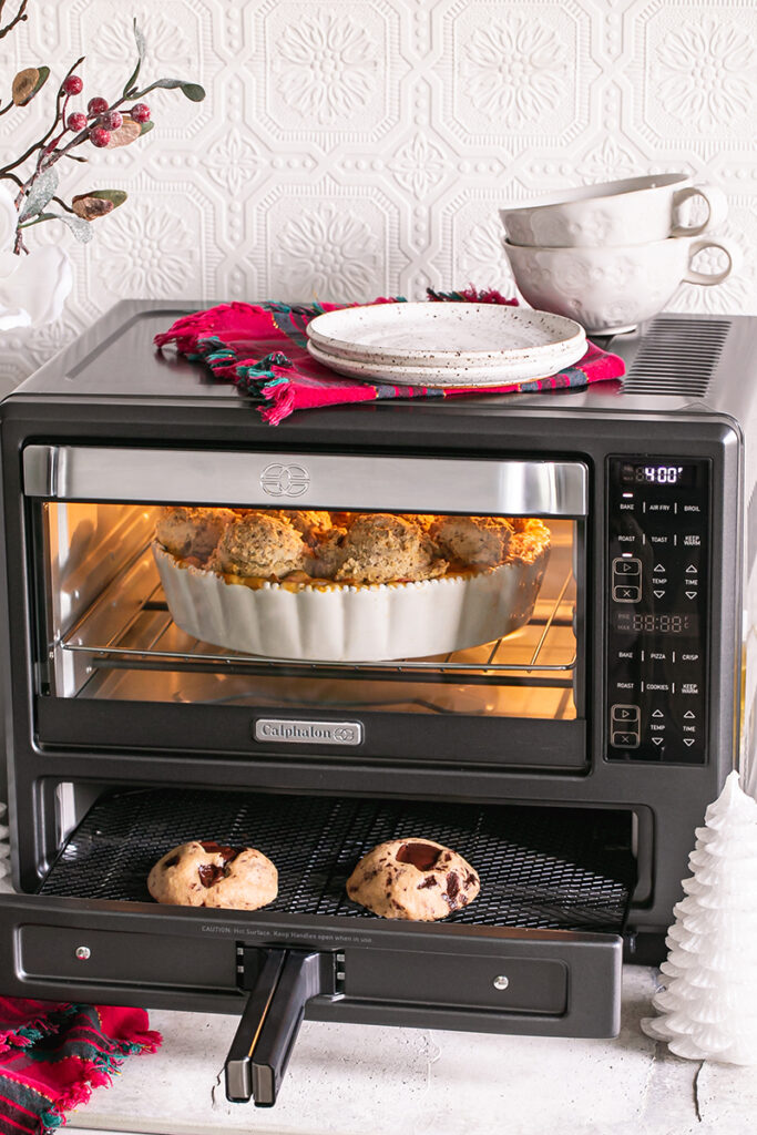 pot pie casserole in the air fryer oven with the light on, then the chocolate chunk cookies in the air fryer portion of the oven with the drawer pulled out so you can see the cookies