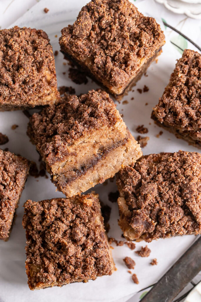 a close up of almond flour coffee cake sliced into squares on a parchment lined wire cooling rack
