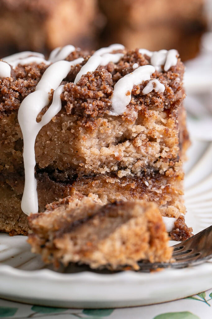 a very close up of an iced piece of almond flour coffee cake with a piece of cake on the fork