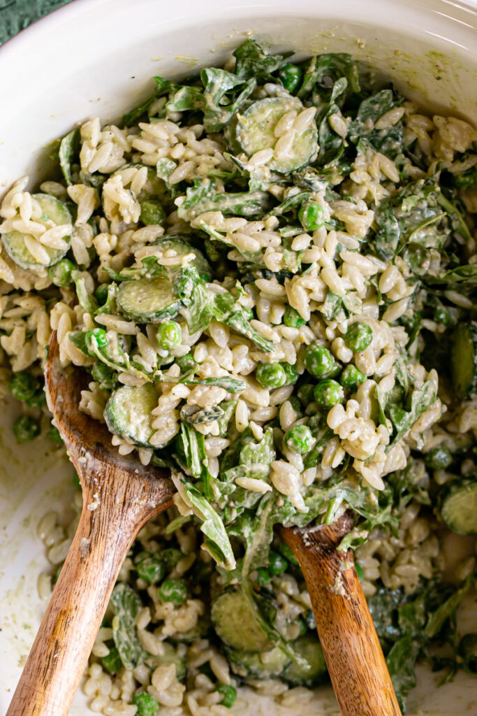 all of the lemon basil orzo salad ingredients tossed together in a large bowl with the salad tongs in the bowl