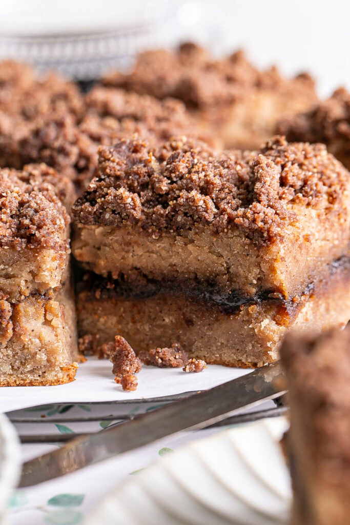 close up of almond flour coffee cake sliced into squares on a parchment lined wire cooking rack