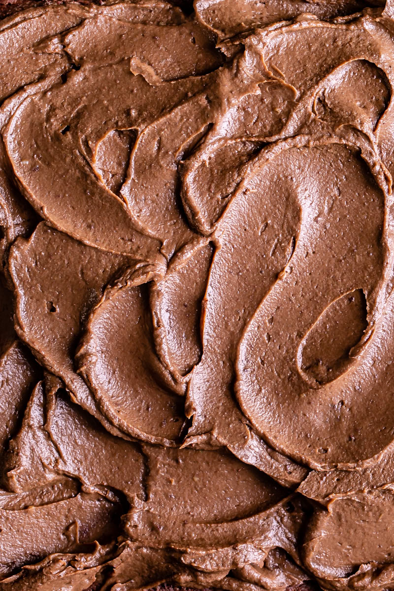 a close up of avocado chocolate frosting swirled with a spoon to create swirls in the frosting