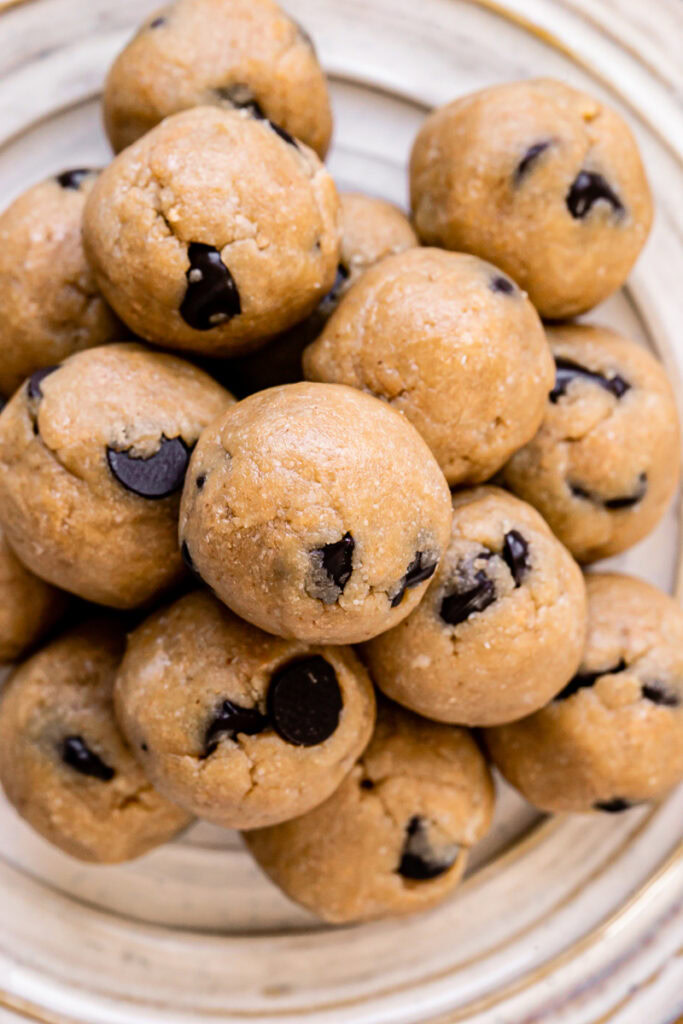 over head shot of almond flour chocolate chip cookie dough bites piled on top of one another on a plate