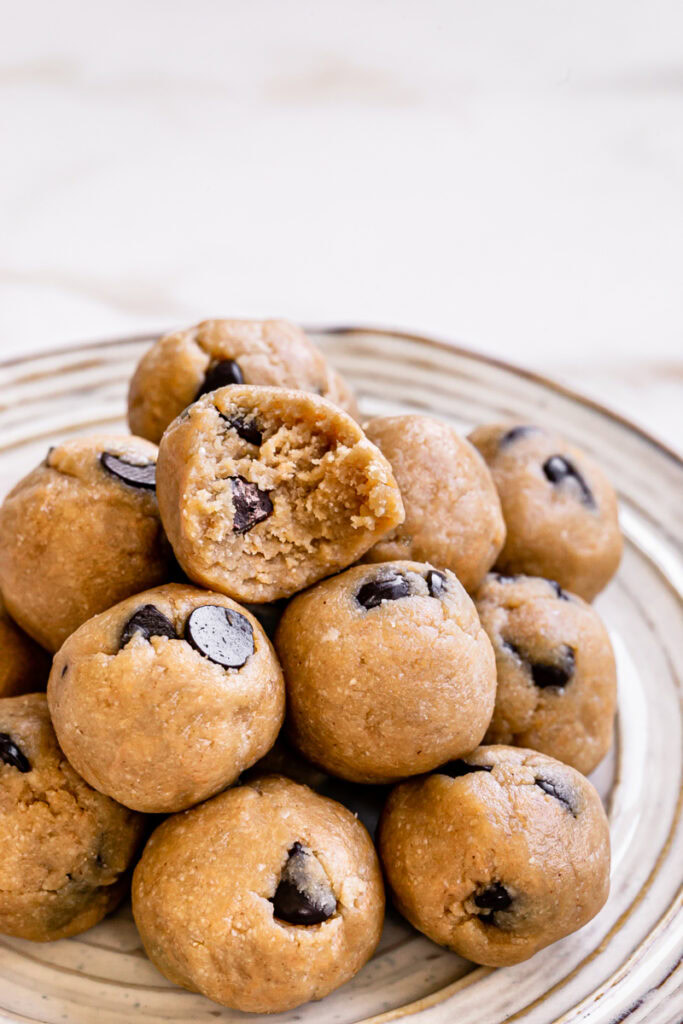 almond flour chocolate chip cookie dough bites piled on top of one another on a plate with a bite taken out of the top one