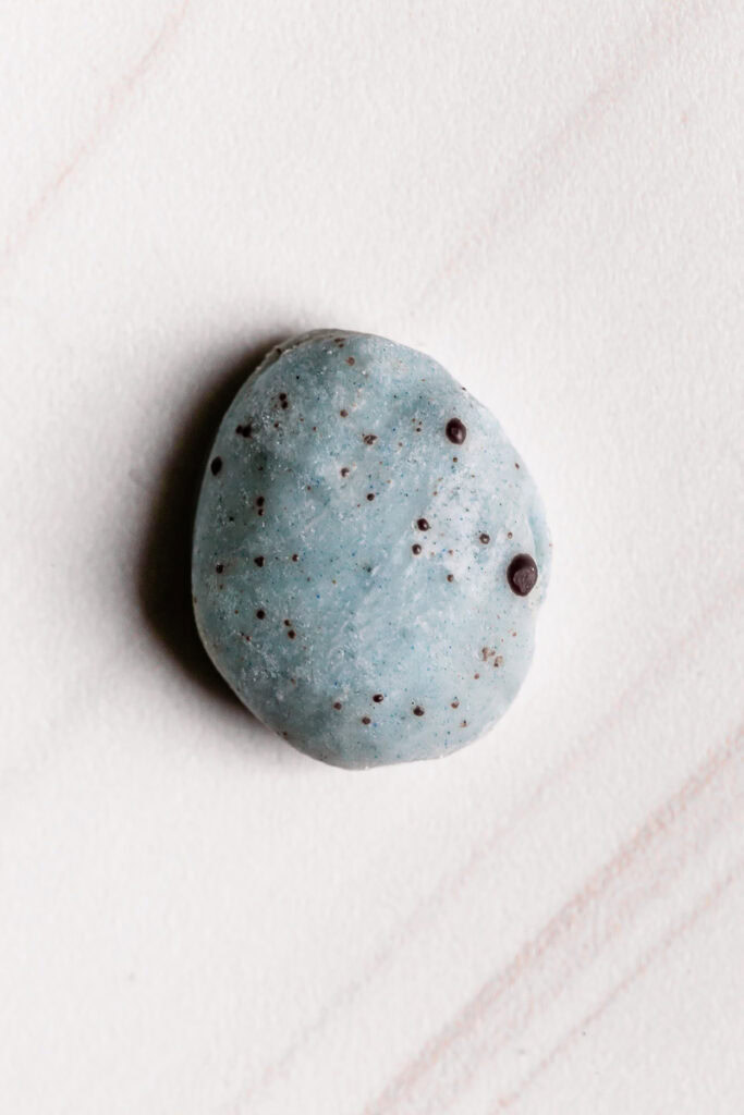 a single robin's egg white chocolate covered almond speckled with dark chocolate