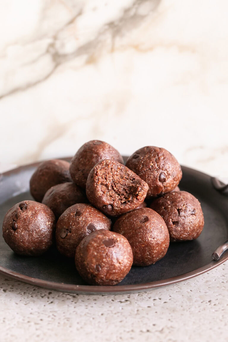 Sunflower seed chocolate brownies bites rolled and stacked on a round metal plate, the top bite with a bite taken out of it.