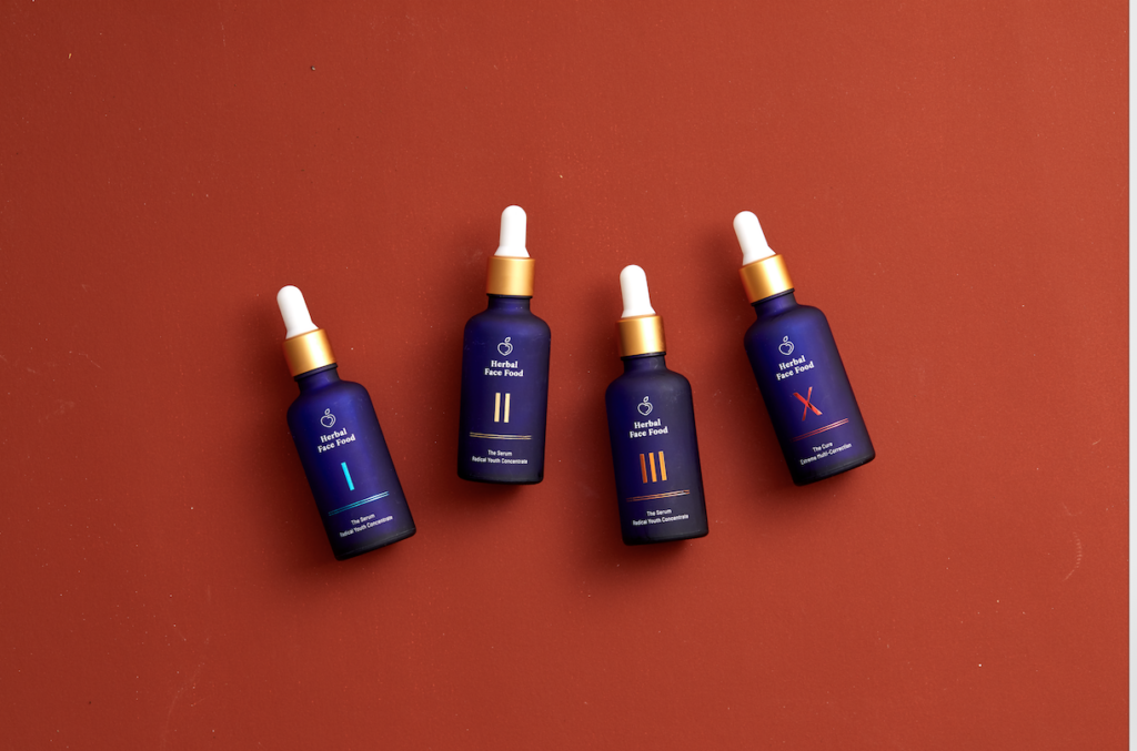 all of the herbal face food serums laid next to each other on a red background