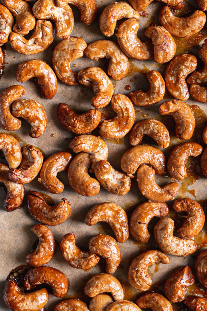 roasted golden brown ginger-agave cashews on a parchment lined baking sheet