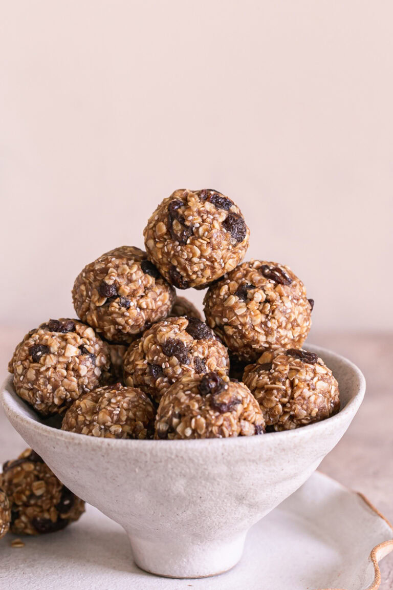 a close up shot of No-Bake Oatmeal Raisin Protein Cookie Dough Bites piled on top of each other in a bowl