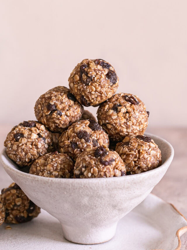 a close up shot of No-Bake Oatmeal Raisin Protein Cookie Dough Bites piled on top of each other in a bowl