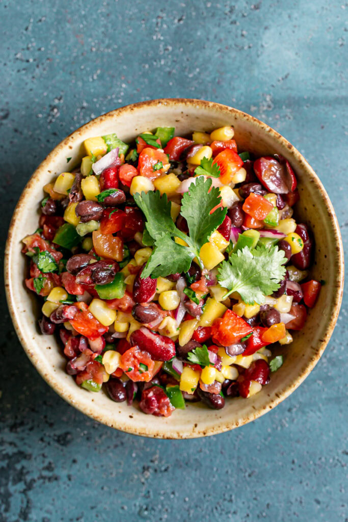 a bowl of cowboy caviar bean dip garnished with fresh cilantro