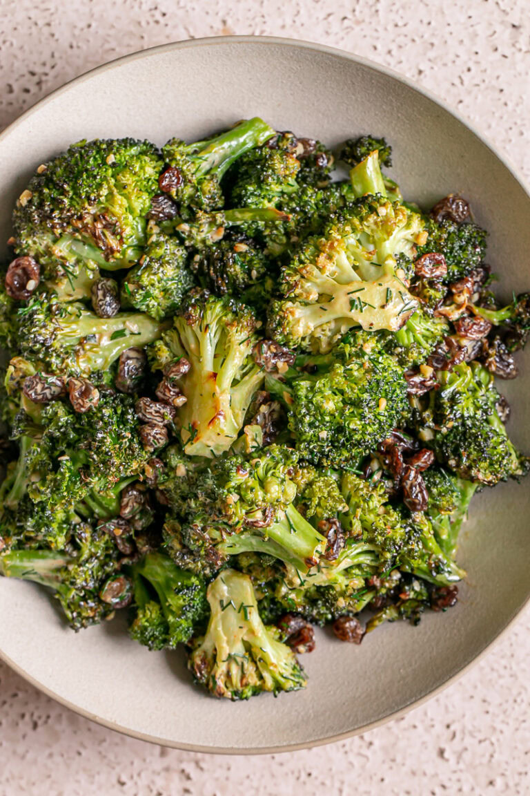 a bowl of broccoli tossed with fresh dill and raisins and a harissa tahini dressing
