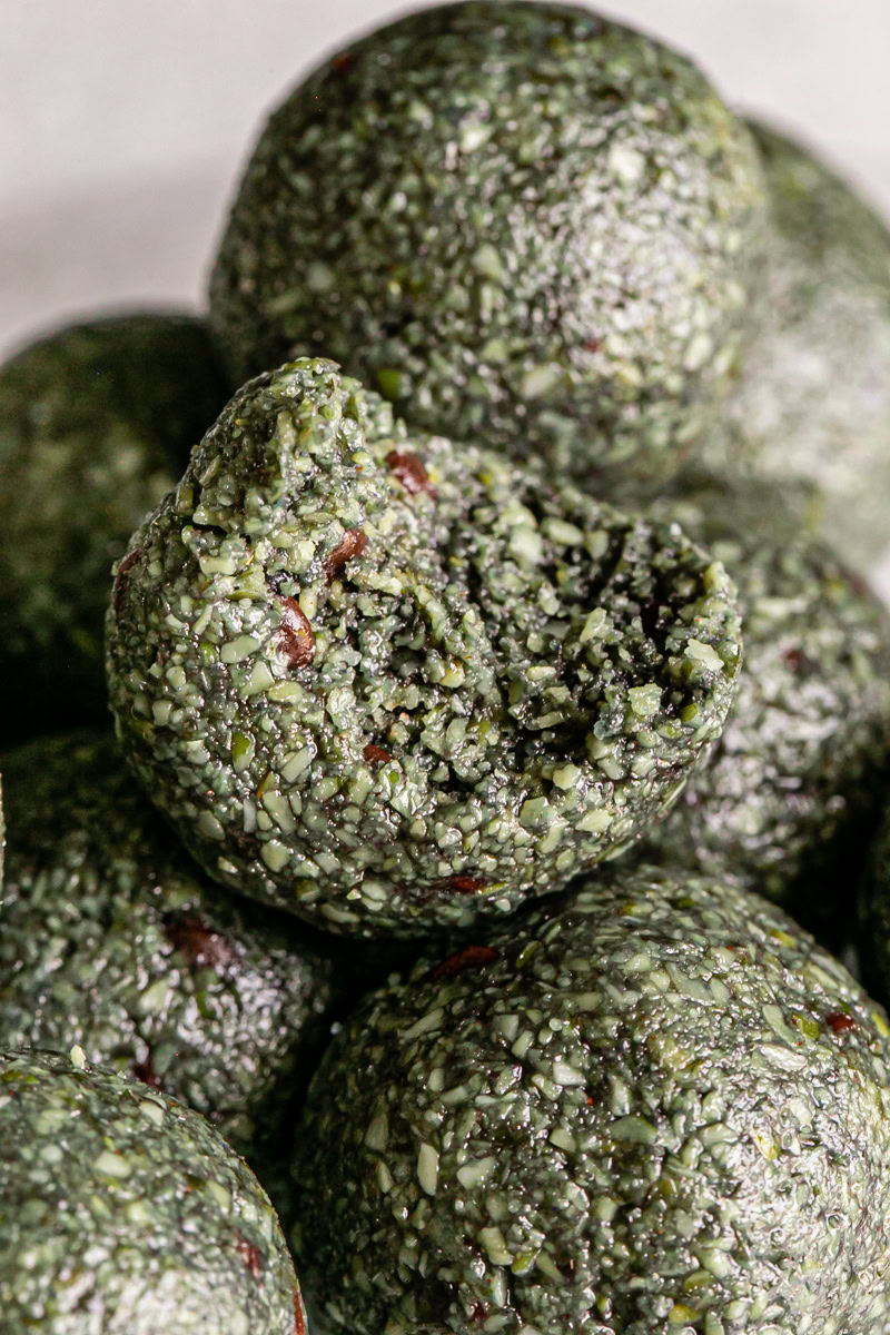 close up macro shot of Spirulina Pumpkin Seed Chocolate Chip Bites with a bite out of the middle one