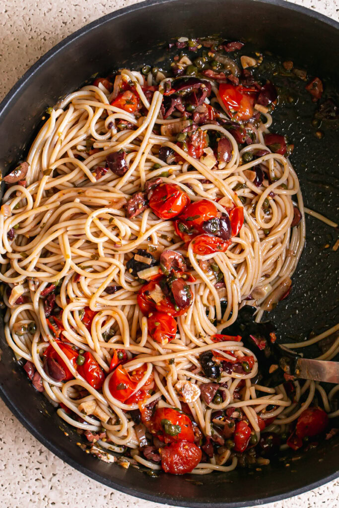 spaghetti tossed in with the cooked cherry tomato puttanesca sauce ingredients