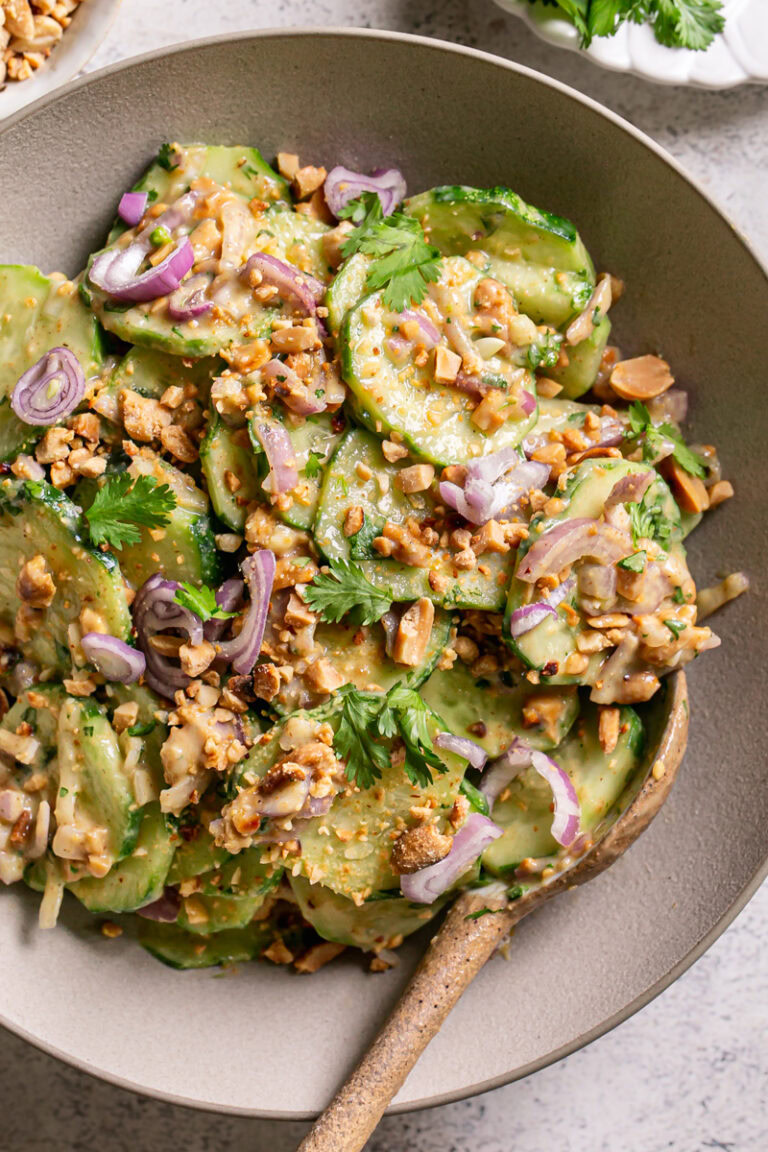 a close up of a bowl of Miso Cucumber Salad with Shallot and Roasted Peanuts with a serving spoon in it