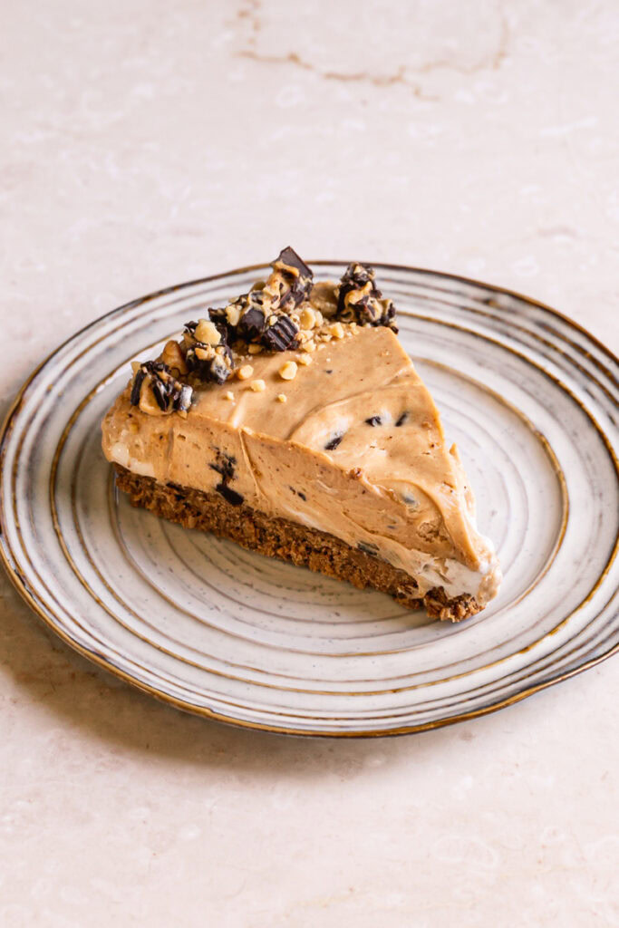 a slice of an overhead shot of sliced No-Bake Peanut Butter Cup Pie on a plate garnished with chopped peanut butter cups and peanuts