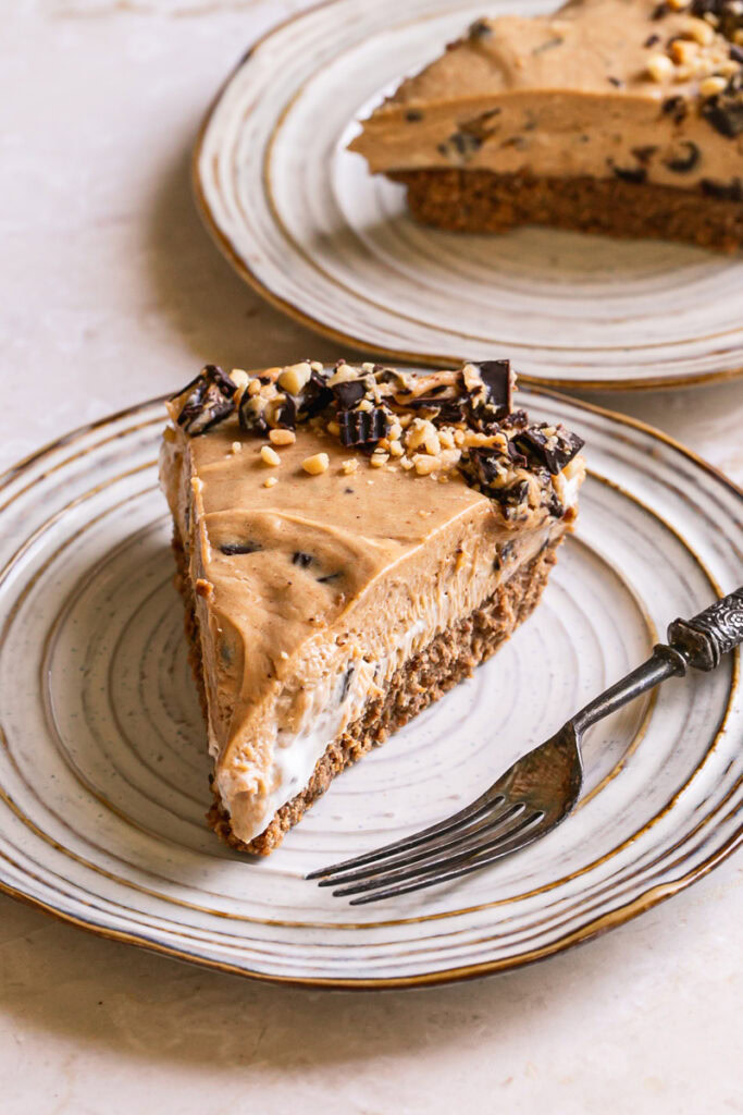 a slice of No-Bake Peanut Butter Cup Pie on a plate with a fork and another slice of pie on a another plate behind it