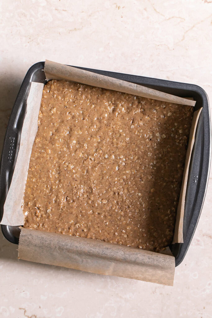half of the peanut butter oat crumb mixture pressed into a parchment lined 8x8 baking pan