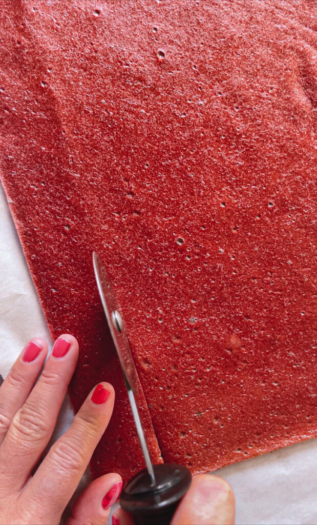 action shot of slicing the fruit leather with a pizza cutter
