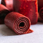close up of a rolled up strawberry mango fruit roll up with others rolled up in the background