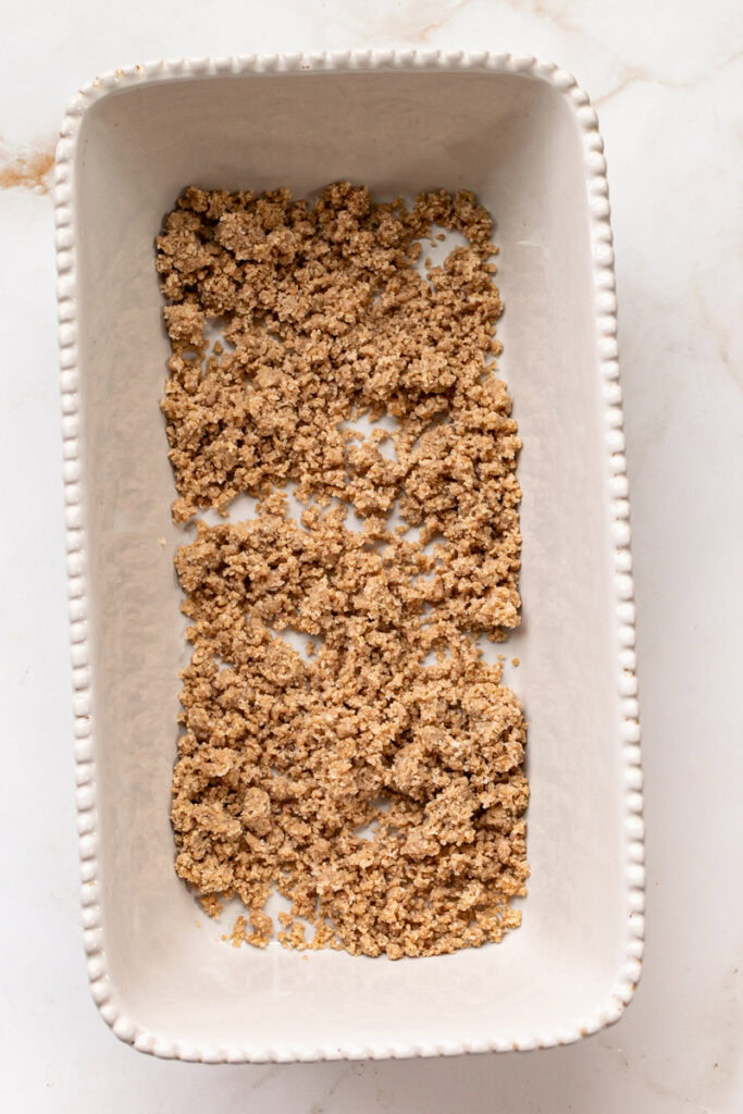 almond flour cookie dough crumble sprinkled in the bottom of a loaf pan