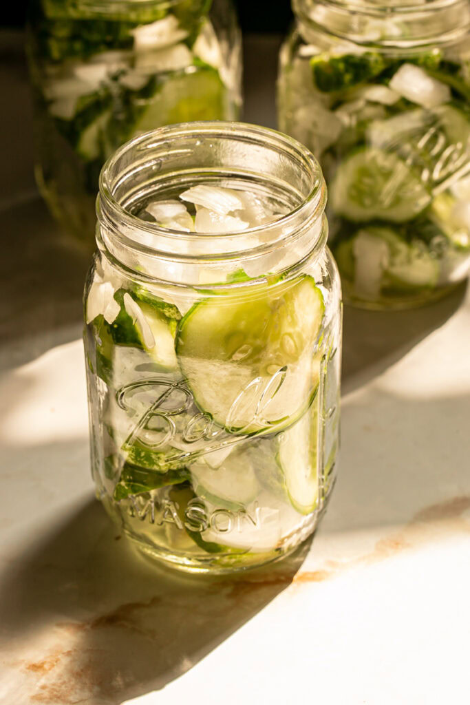 cucumber slices and sliced onion stuffed into 16 ounce mason jars