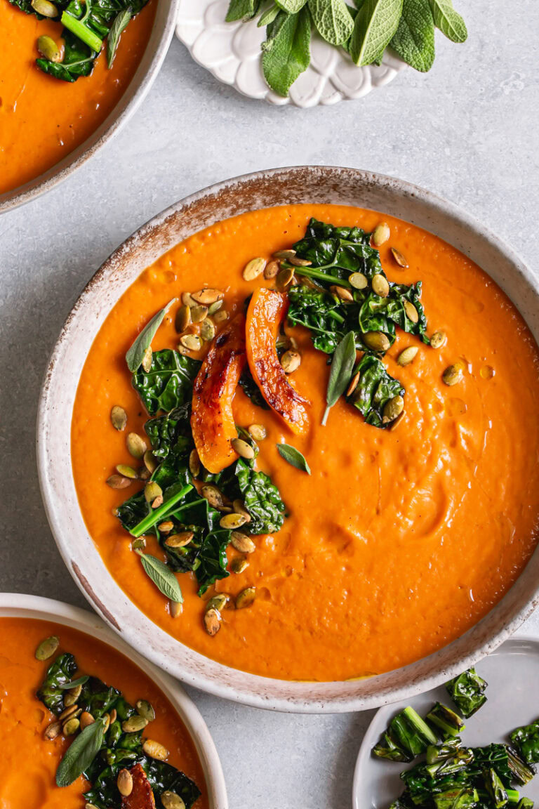 three bowls of Roasted Butternut Squash Tomato Soup garnished with with Crispy Kale and toasted pumpkin seeds and fresh sage leaves