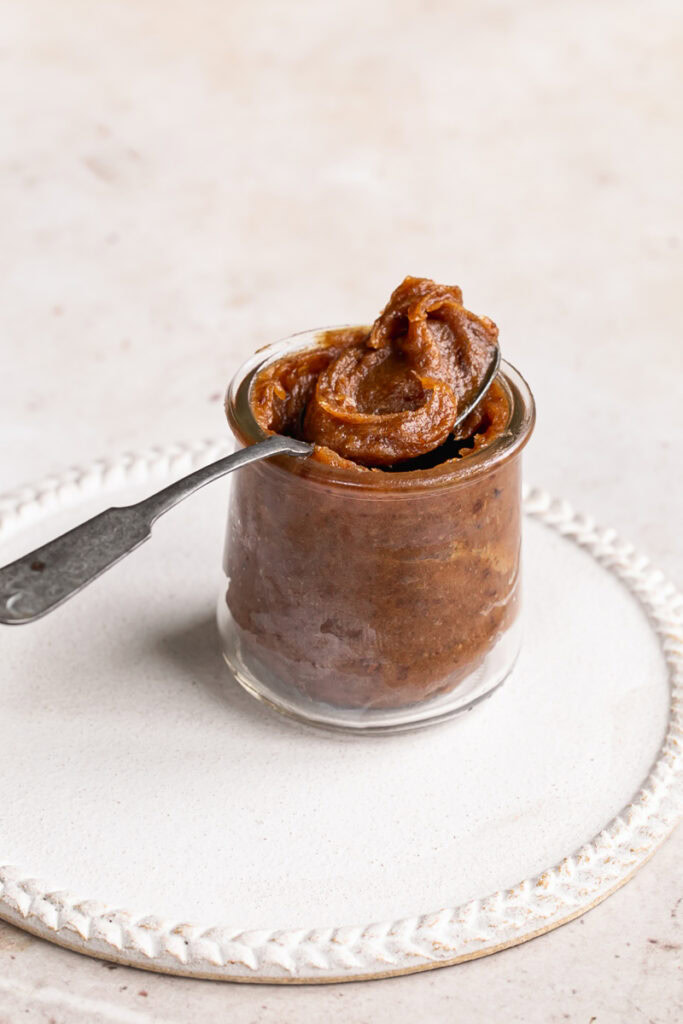a jar of date caramel with a spoonful of caramel resting on the mouth of the jar