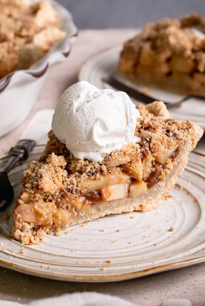 a close up of a slice of healthy dutch apple pie with a scoop of vanilla ice cream on top