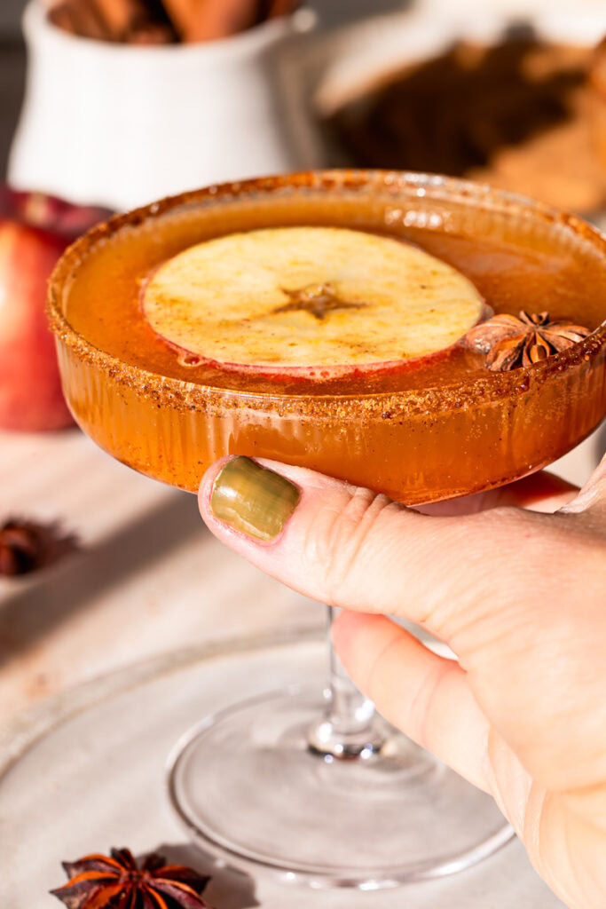 close up of a hand holding a pumpkin apple cider mocktail