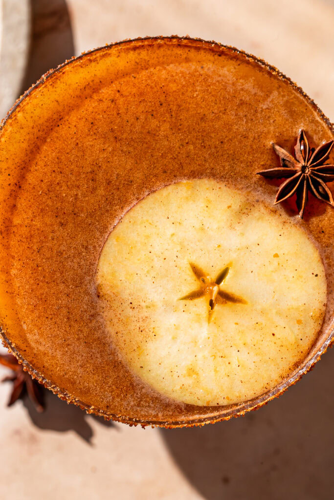 overhead closeup shot of a pumpkin apple cider mocktail with an apple slice and star anise in the glass