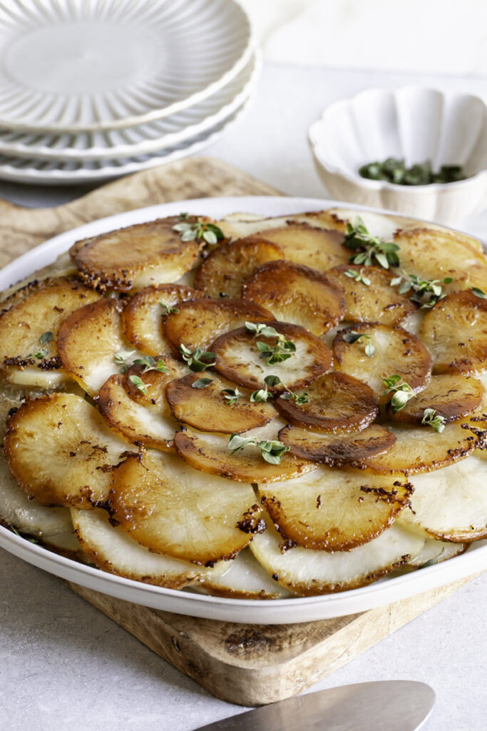 3/4 shot of Pommes Anna skillet potatoes on a plate with small plates in the background
