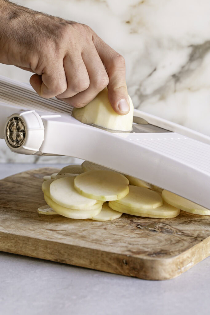 action shot of slicing potatoes with a mandolin slicer