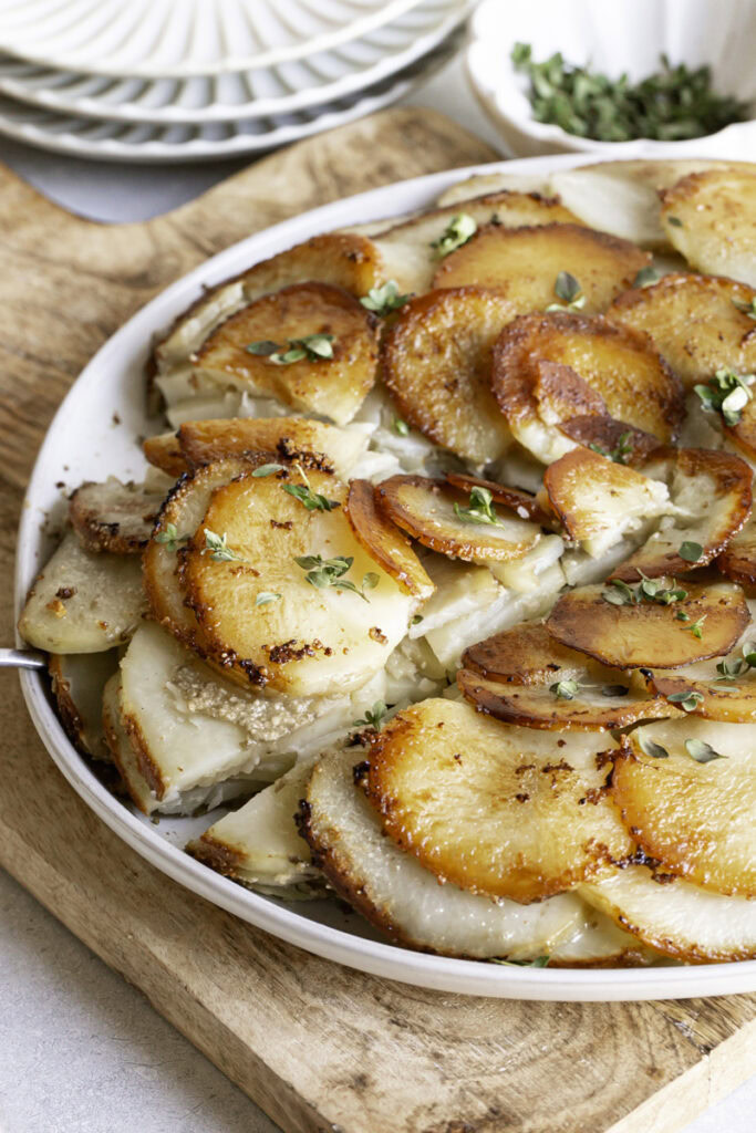 3/4 photo of Pommes Anna skillet potatoes on a plate, sliced