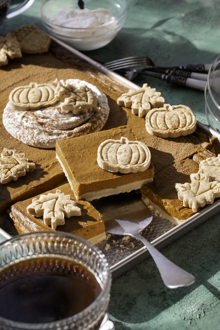 3/4 shot of sheet pan pumpkin pie, some of the pie cut into squares, one piece on a pie server
