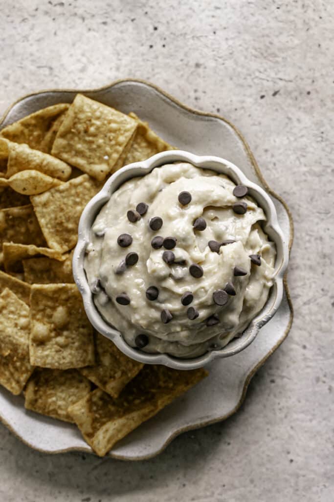 overhead shot of a bowl of High Protein Vegan Cannoli Dip on a plate with cinnamon churro chips around it