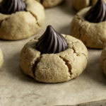 a close up of a Almond Flour Peanut Butter Blossom Cookie on a parchment lined baking sheet.