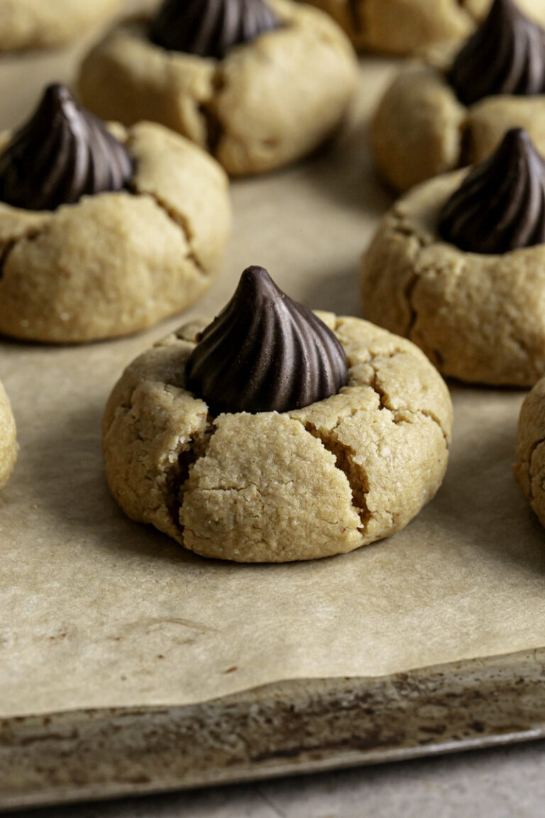 a close up of a Almond Flour Peanut Butter Blossom Cookie on a parchment lined baking sheet.