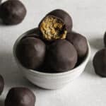 Chocolate Peanut Butter Almond Flour Date Bites in a small bowl, the top one with a bite taken out of it.