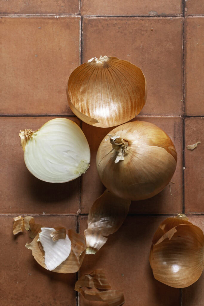 a whole sweet yellow onion and a cut half sweet yellow onion.